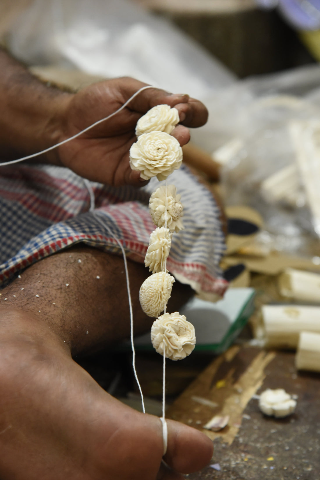 Artisan holding six traditional flower designs handmade from sholapith