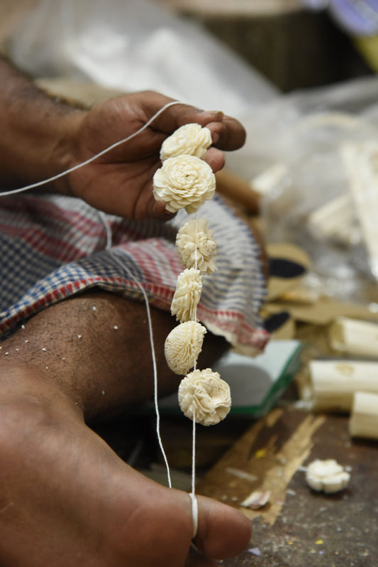 Artisan holding six traditional flower designs handmade from sholapith